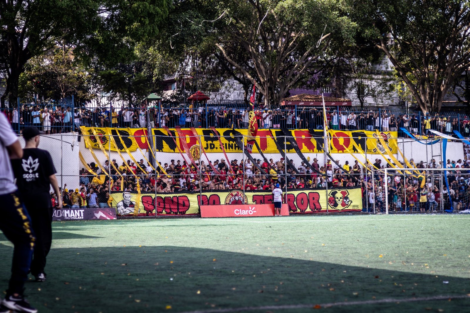 Torcida com bandeiras e marcas junto ao campo
