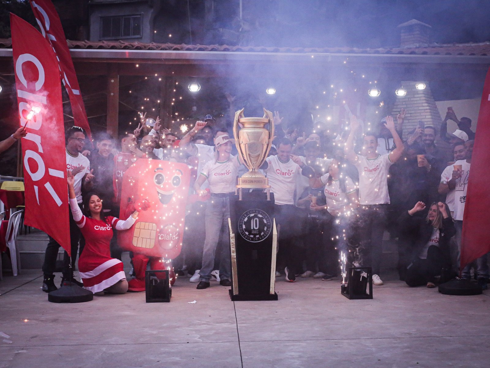 Taça da competição em celebração com o mascote da Claro